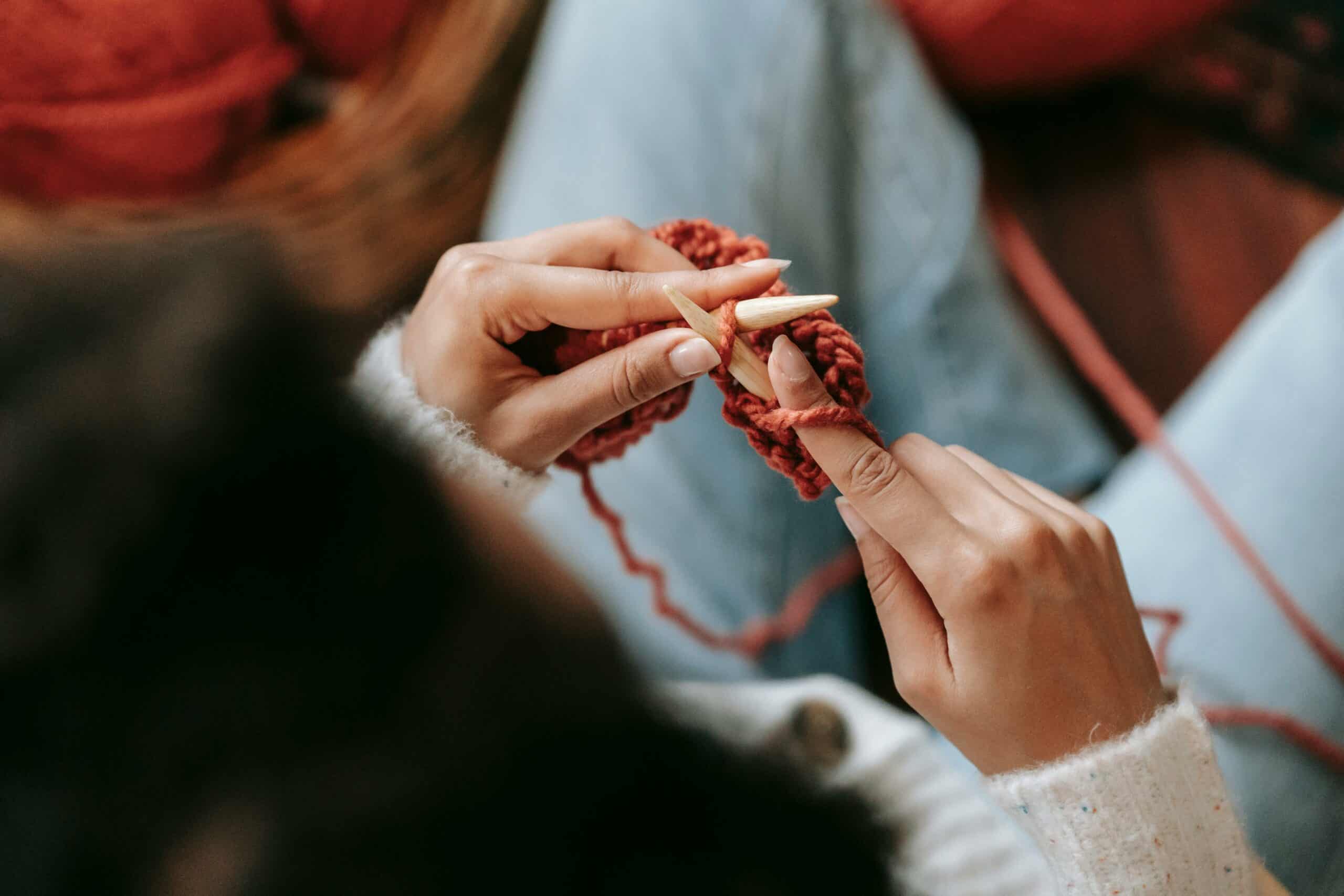 Frau strickt mit Wolle und Nadeln.